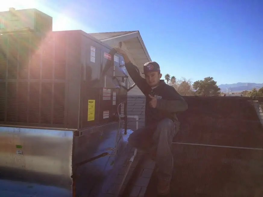 HVAC technician performing Air Duct Repair on a rooftop unit in Logansport