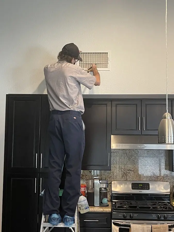Technician inspecting an air vent during HVAC service in Logansport